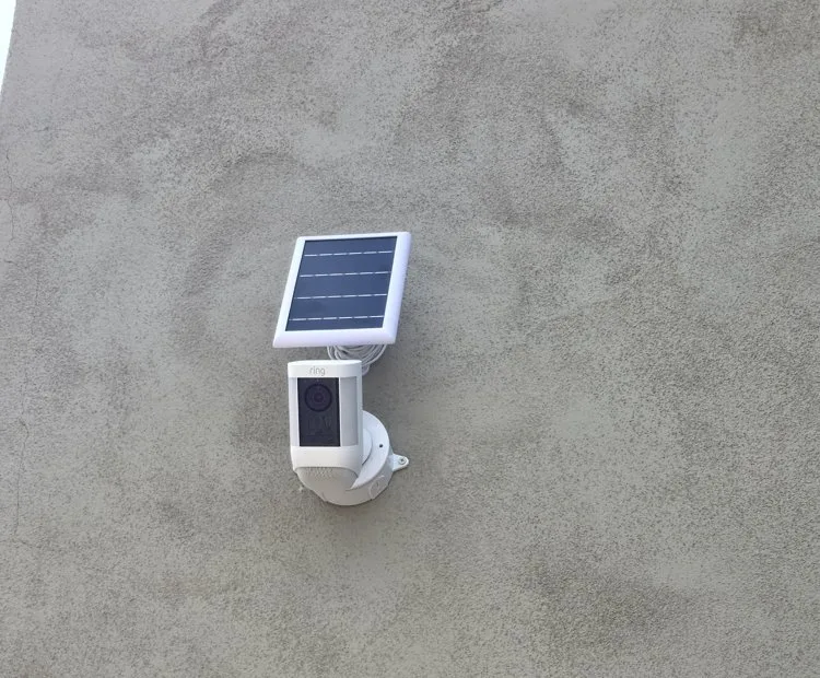 Solar-powered security camera installed on a stucco wall